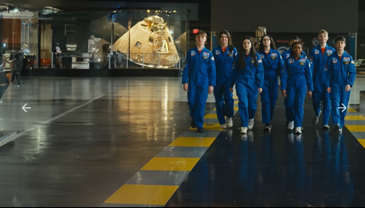 Irish teens in blue flight suits walking through a space museum for the Space Camp Challenge.